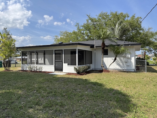 rear view of property with a lawn, fence, and a sunroom