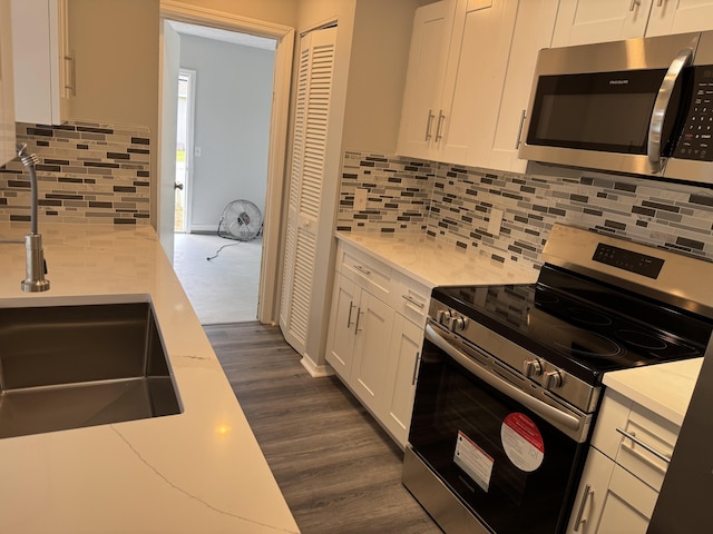 kitchen featuring stainless steel appliances, backsplash, dark wood finished floors, and white cabinets