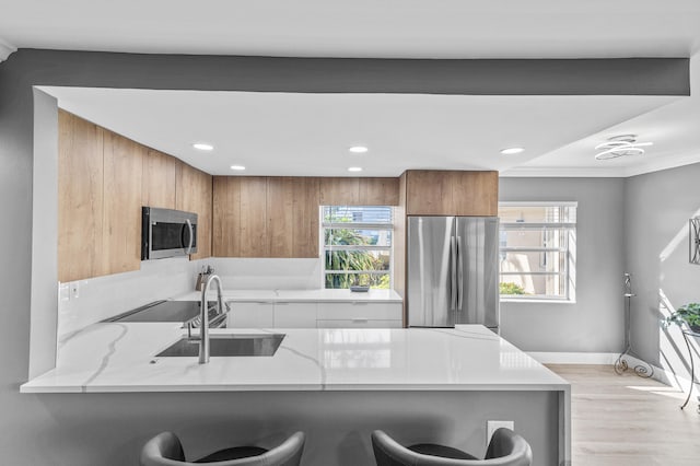 195 Burgundy Unit E, Delray Beach, FL 33484 - kitchen featuring a breakfast bar area, light stone counters, brown cabinetry, a peninsula, and appliances with stainless steel finishes