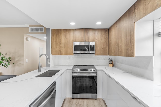 kitchen featuring visible vents, backsplash, light stone countertops, stainless steel appliances, and a sink