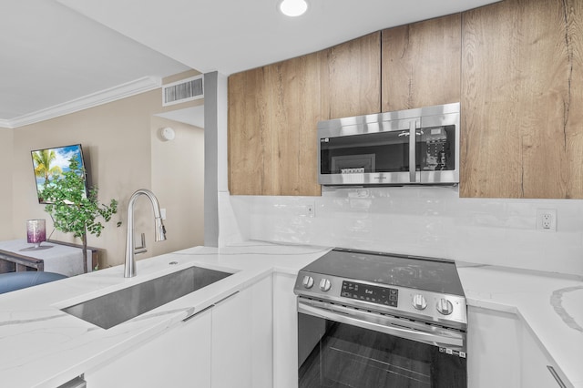 kitchen with a sink, visible vents, light stone counters, and appliances with stainless steel finishes