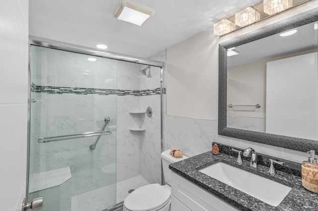 full bath with a marble finish shower, vanity, toilet, and tile walls