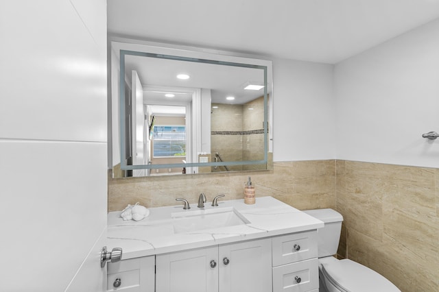 bathroom featuring vanity, tile walls, and toilet