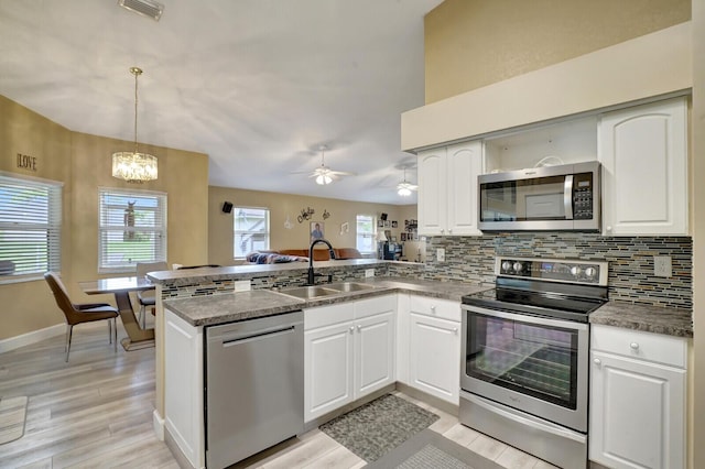 kitchen featuring visible vents, decorative backsplash, appliances with stainless steel finishes, a peninsula, and a sink