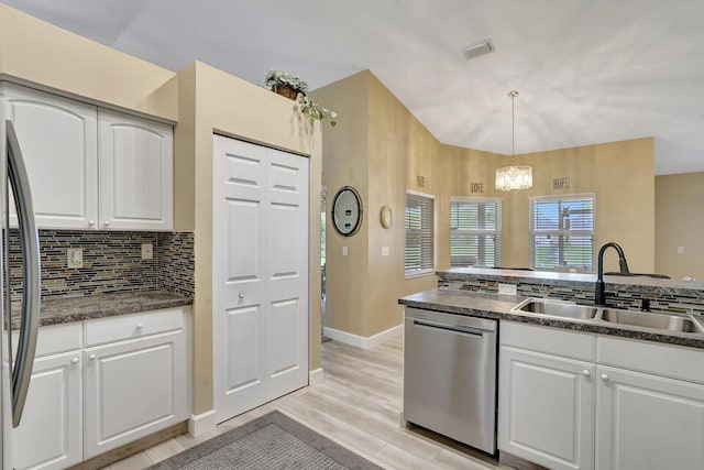 kitchen with a sink, a notable chandelier, dark countertops, and appliances with stainless steel finishes