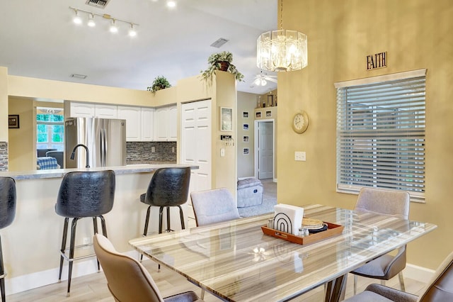 dining room featuring an inviting chandelier, baseboards, visible vents, and light wood finished floors