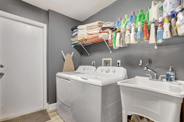 laundry room featuring a sink, a textured ceiling, separate washer and dryer, light wood finished floors, and laundry area