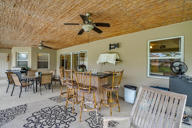 view of patio with outdoor dry bar, outdoor dining area, and a ceiling fan