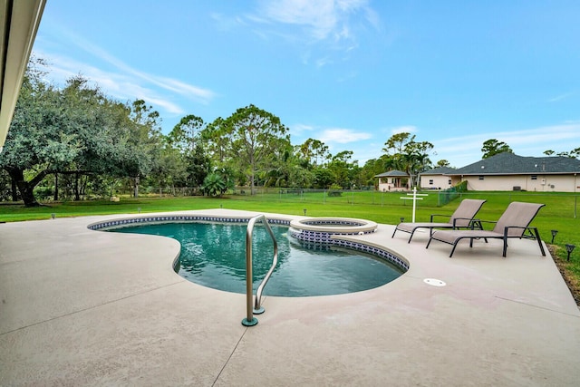 view of pool with fence, a lawn, a pool with connected hot tub, and a patio area