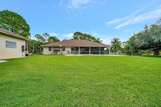 rear view of house featuring stucco siding, a lawn, and a sunroom