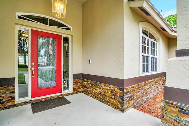 entrance to property featuring stone siding and stucco siding