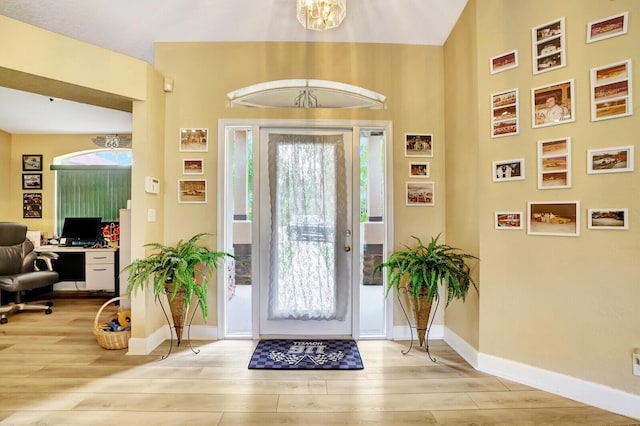 entrance foyer featuring baseboards, a notable chandelier, and wood finished floors