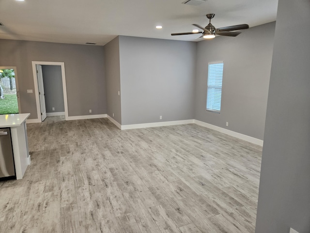 spare room with plenty of natural light, light wood finished floors, and ceiling fan