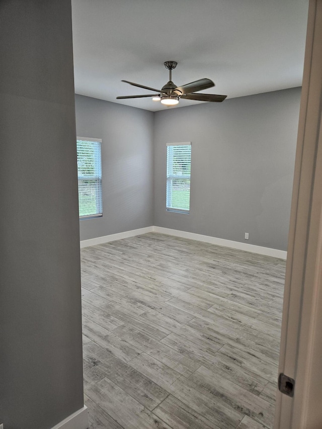 spare room with baseboards, wood finished floors, and a ceiling fan