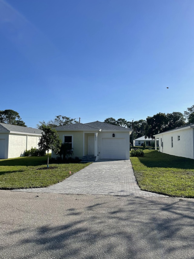 view of front of house with a garage, decorative driveway, and a front lawn