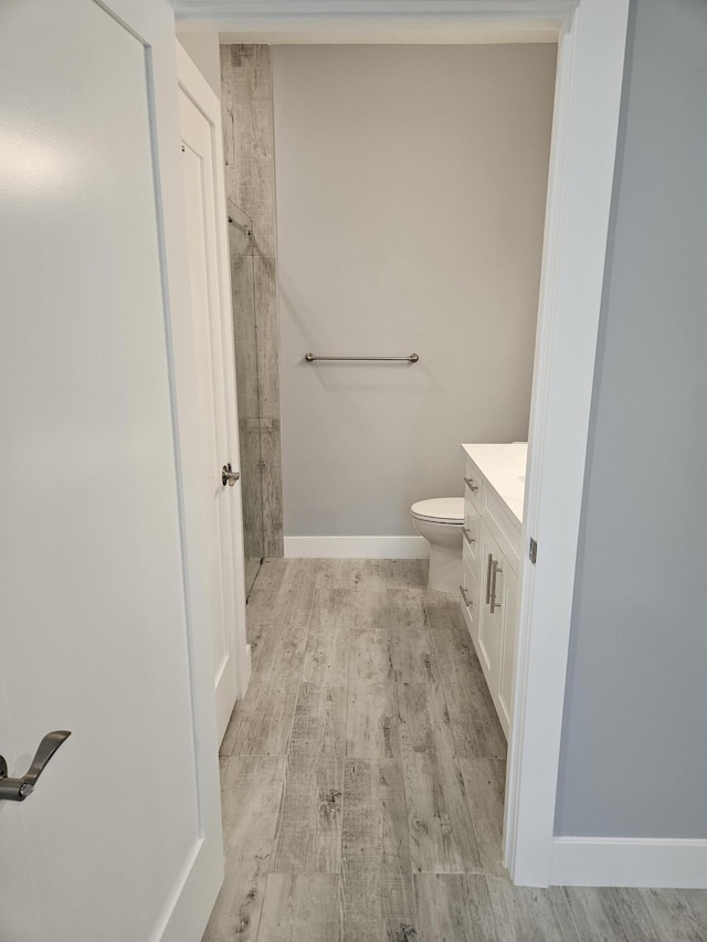 full bathroom featuring vanity, toilet, wood finished floors, and a stall shower