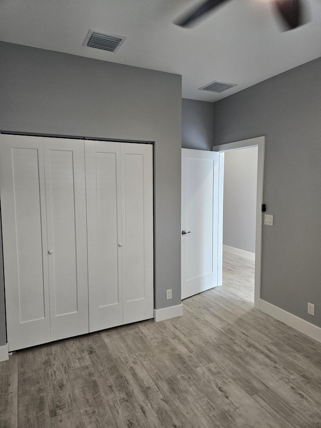 unfurnished bedroom with a closet, visible vents, baseboards, and wood finished floors