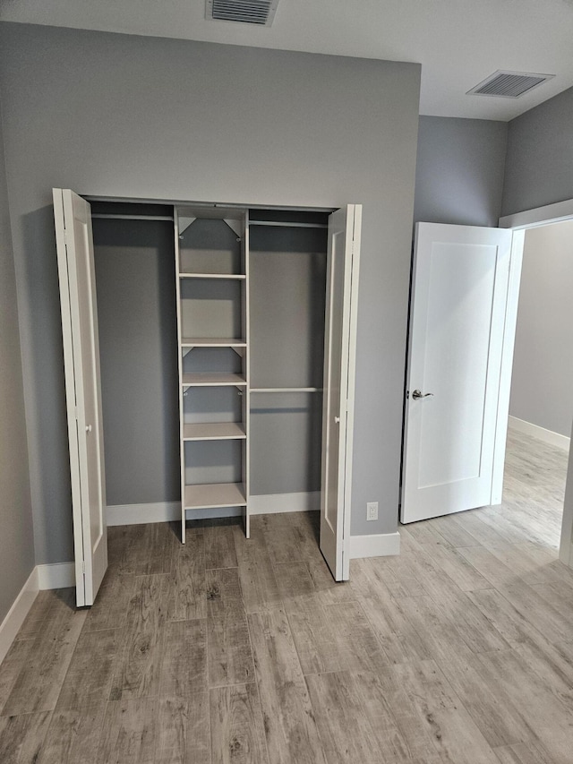 unfurnished bedroom featuring visible vents, baseboards, and wood finished floors