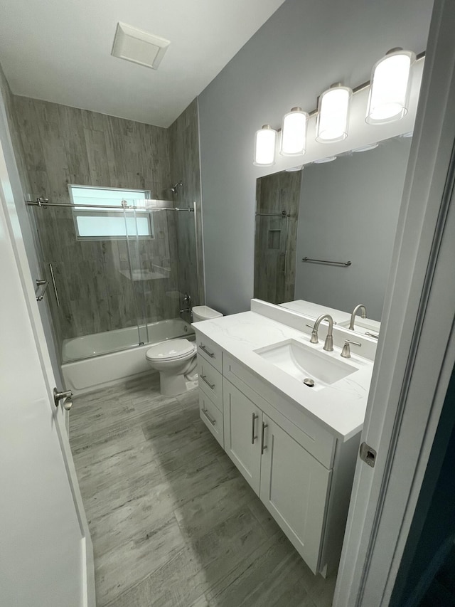 bathroom featuring combined bath / shower with glass door, toilet, wood finished floors, and vanity