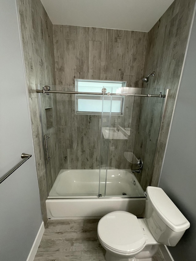 full bathroom with wood finished floors, toilet, baseboards, and bath / shower combo with glass door