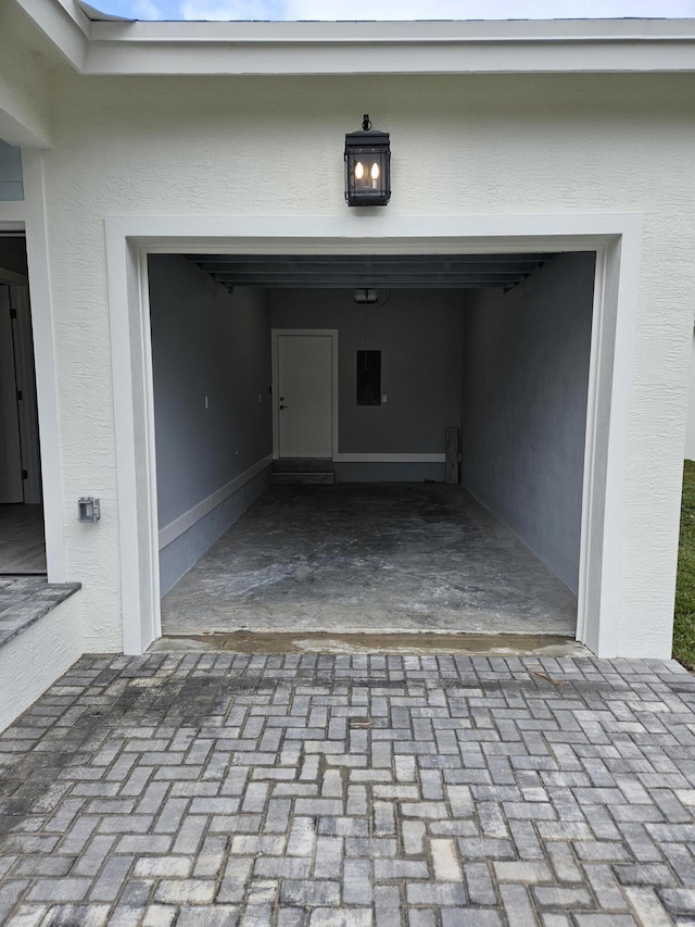 garage with decorative driveway and electric panel