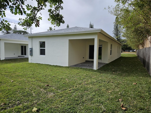 rear view of house featuring a patio area, stucco siding, a lawn, and fence