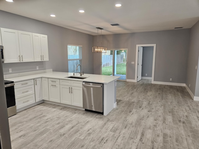 kitchen featuring a peninsula, a sink, stainless steel appliances, light countertops, and white cabinets