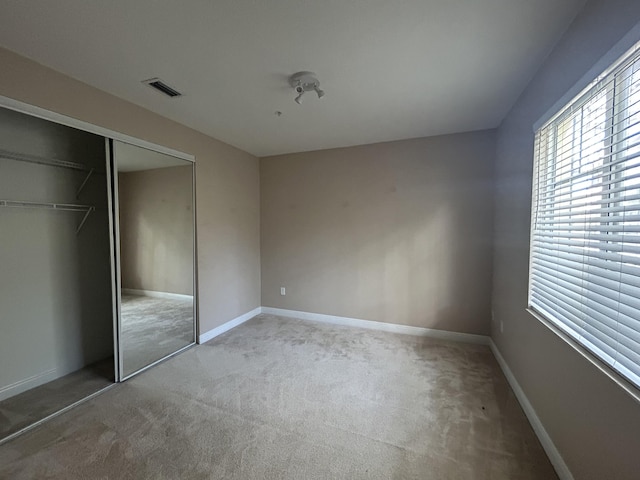 unfurnished bedroom with a closet, visible vents, carpet flooring, and baseboards