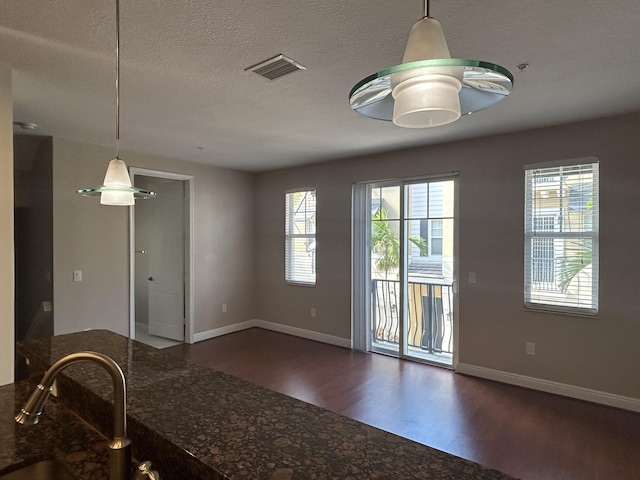 kitchen with visible vents, a textured ceiling, dark wood-type flooring, and baseboards