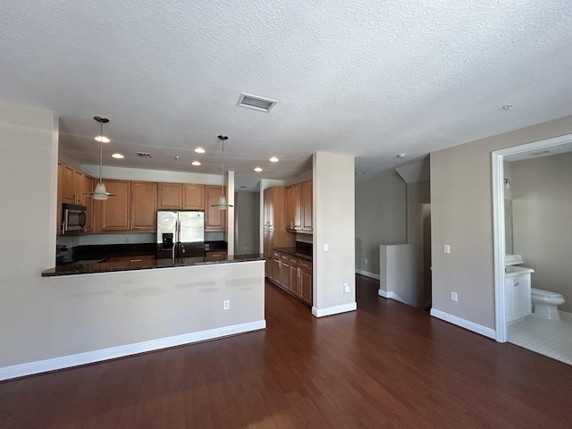 kitchen featuring dark countertops, stainless steel appliances, dark wood-type flooring, and baseboards