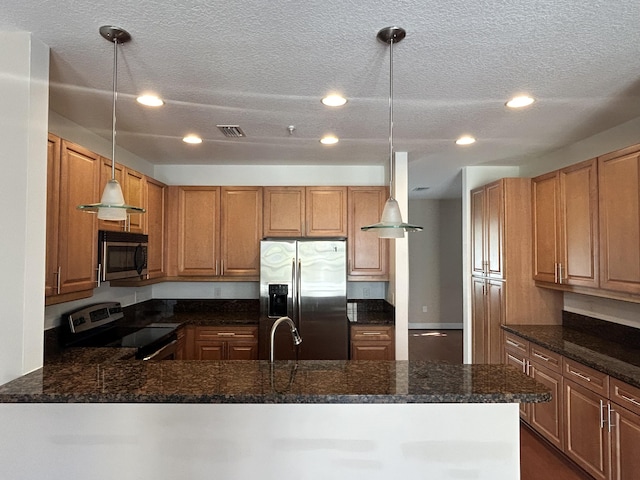 kitchen featuring dark stone countertops, visible vents, a peninsula, stainless steel appliances, and decorative light fixtures