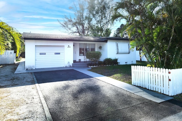 ranch-style house with stucco siding, an attached garage, driveway, and fence