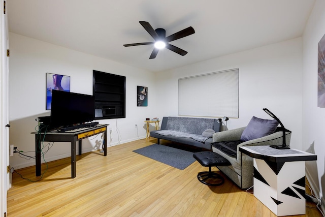 living area featuring baseboards, ceiling fan, and wood finished floors