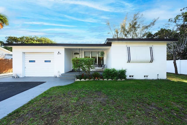 ranch-style home featuring an attached garage, fence, a front yard, stucco siding, and driveway