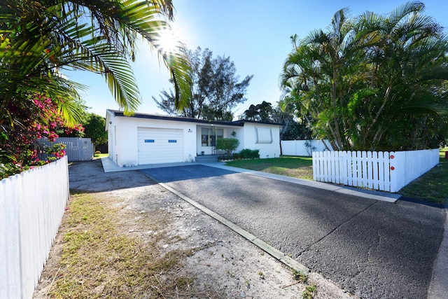 ranch-style home featuring a fenced front yard, stucco siding, an attached garage, and concrete driveway