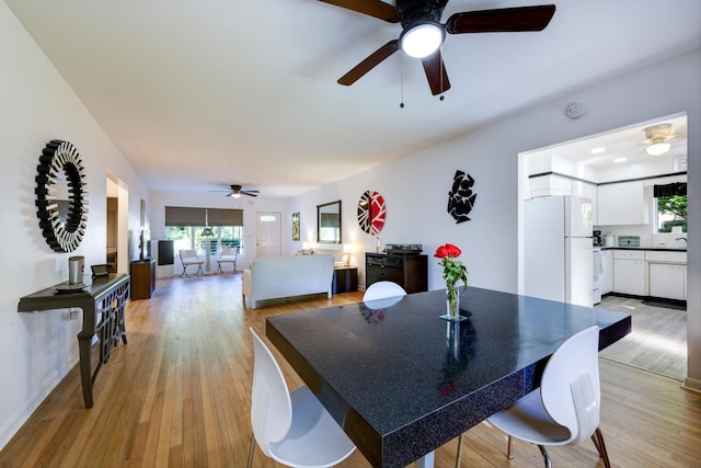 dining area with light wood-type flooring, a healthy amount of sunlight, and a ceiling fan