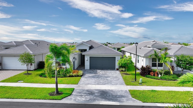 ranch-style house with a front lawn, a tiled roof, stucco siding, decorative driveway, and an attached garage