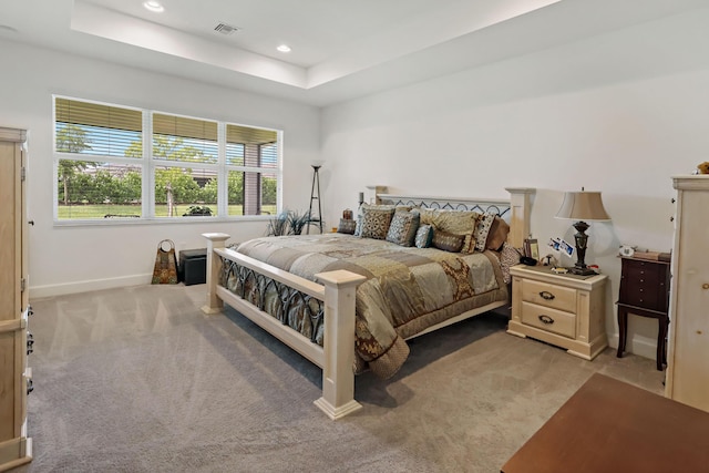 bedroom with a raised ceiling, recessed lighting, light colored carpet, and visible vents