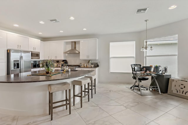 kitchen with a kitchen bar, wall chimney exhaust hood, visible vents, and appliances with stainless steel finishes