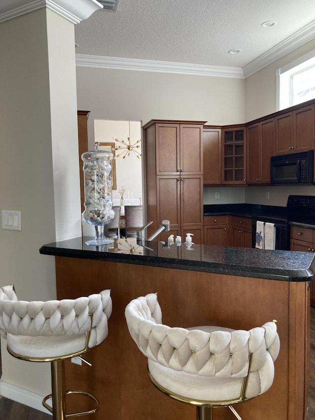 kitchen with glass insert cabinets, crown molding, a kitchen breakfast bar, a textured ceiling, and black appliances