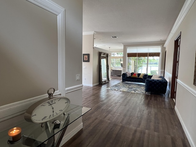 hall with crown molding, dark wood-style floors, visible vents, and a textured ceiling