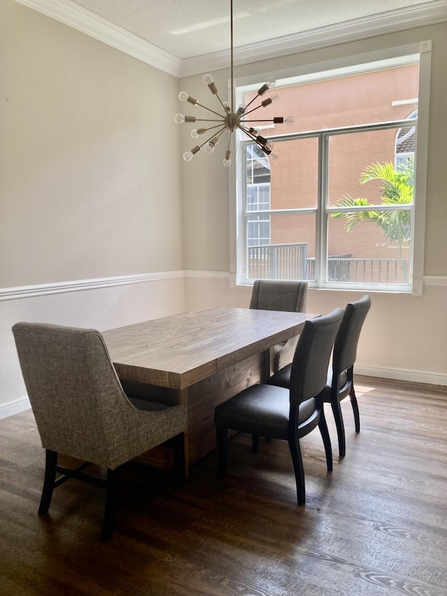 dining room with ornamental molding, wood finished floors, baseboards, and a chandelier