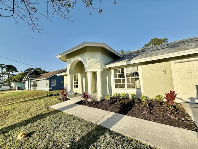 view of front of house with stucco siding, an attached garage, and a front lawn