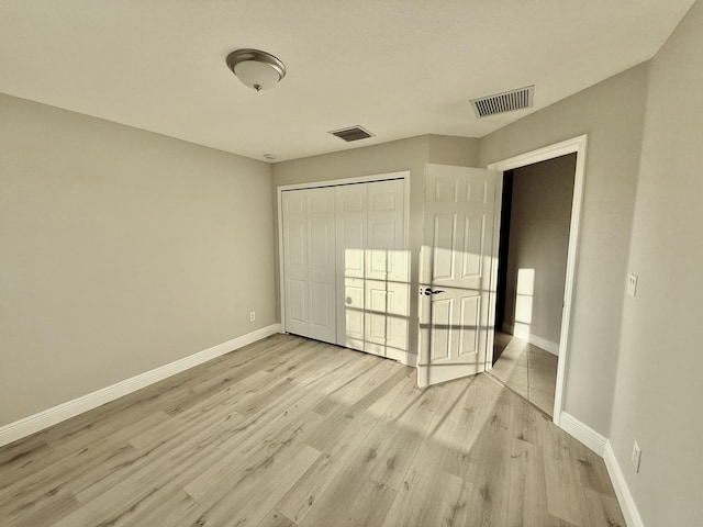 unfurnished bedroom with a closet, visible vents, light wood-type flooring, and baseboards