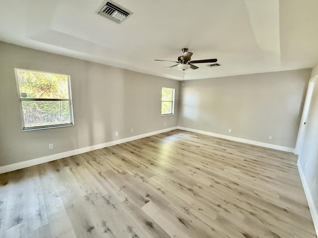 spare room featuring visible vents, baseboards, a ceiling fan, and light wood finished floors