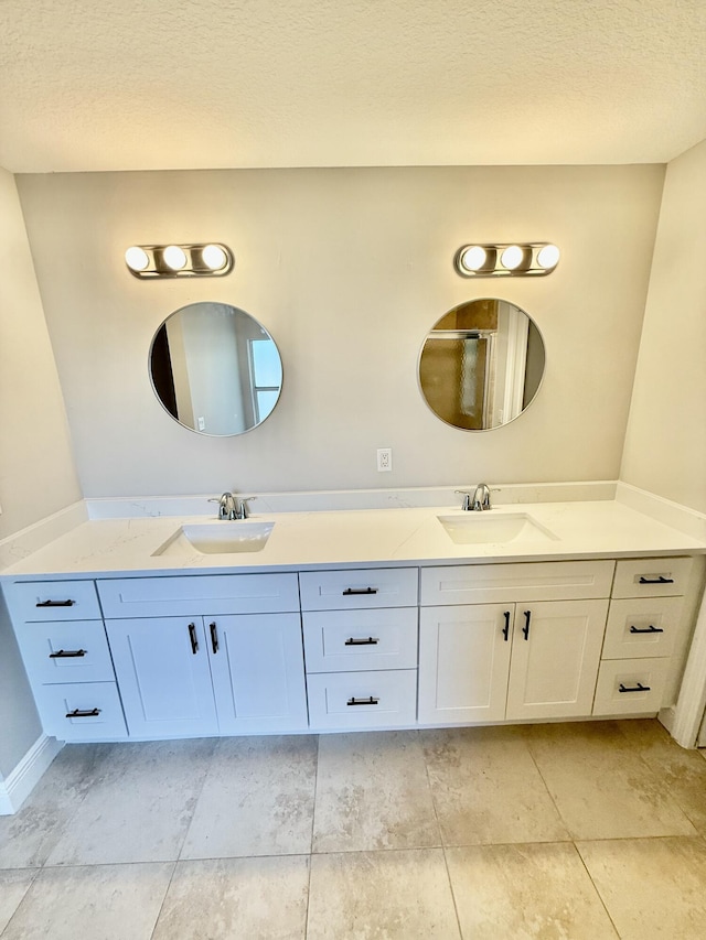 bathroom featuring a sink, a textured ceiling, and double vanity