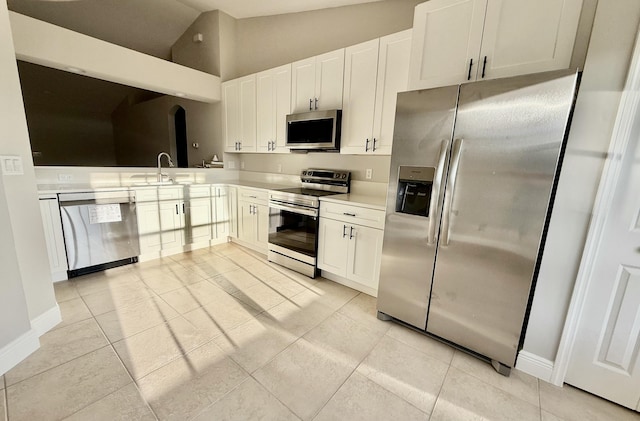 kitchen with light countertops, vaulted ceiling, appliances with stainless steel finishes, white cabinetry, and a sink