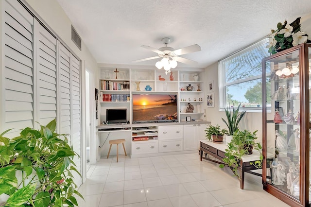 living area with visible vents, a textured ceiling, ceiling fan, and built in desk