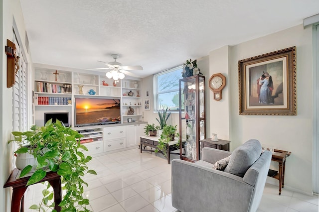 living area with a textured ceiling, built in features, light tile patterned floors, and ceiling fan