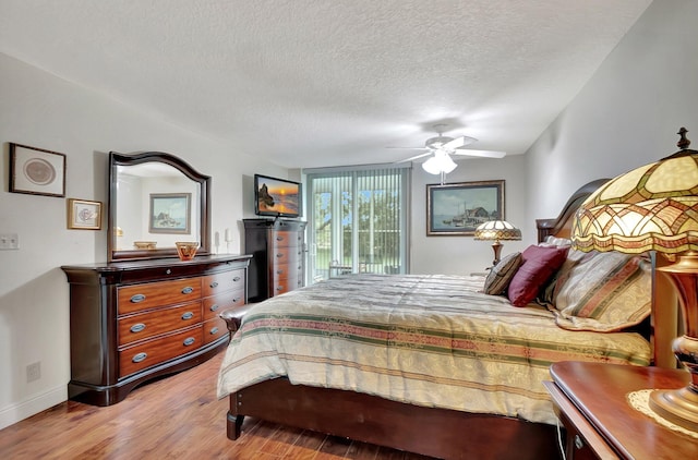 bedroom with baseboards, wood finished floors, a textured ceiling, a ceiling fan, and access to outside